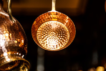 Copper kitchenware pots, pans, jugs hang from the ceiling in t