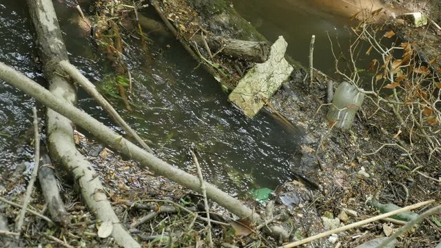 Sad mountain river water contamination with thrash and plastic 4K 2160p 30fps UltraHD footage - Polluted river with garbage bottles and other junk 4K 3840X2160 UHD video 