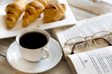 Book and croissants with coffee on the wooden table