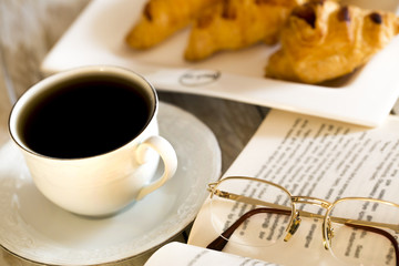 Book and croissants with coffee on the wooden table