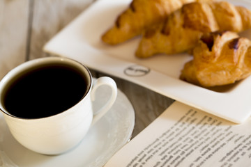 Book and croissants with coffee on the wooden table