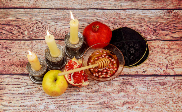 rosh hashanah jewesh holiday torah book, honey, apple and pomegranate over wooden table. traditional  symbols.