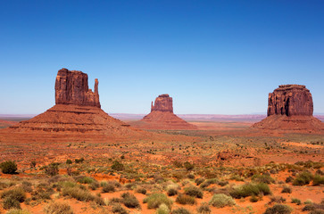 Three sandstone buttes in Monument Valley, Utah is part of the Navajo Tribal Park Reservation and is frequently used as a movie location in western desert scenes.