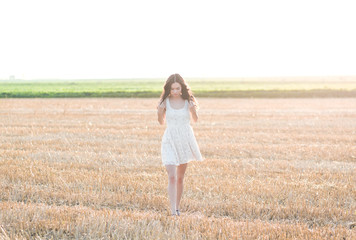 Portrait of beautiful young woman walking through a wheat field.