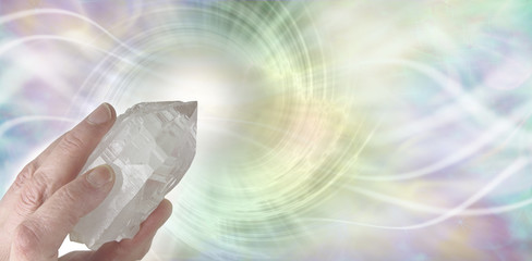 Crystal Therapy Resonance - Female hand pointing a clear quartz terminated crystal upwards on a...