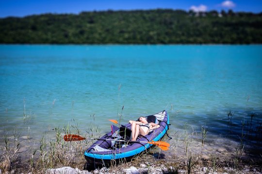 une jeune femme endormie dans son canoë sur un lac bleu