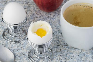 Cup of coffee and two boiled eggs in egg stands.