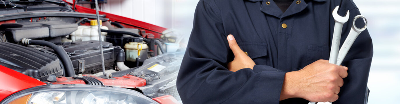 Hands of car mechanic with wrench in garage.