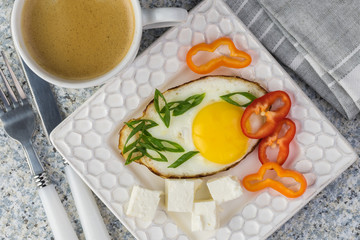 Breakfast with fried egg, fresh vegetables, feta and cup of coffee.