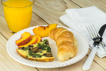 Breakfast with piece of spinach mushroom frittata, croissant and