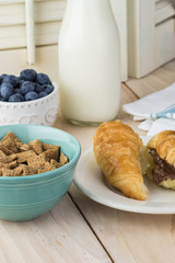 Bowl with wheat cereal and fresh croissantsl for breakfast.