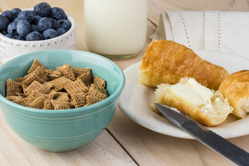 Bowl with wheat cereal and fresh croissantsl for breakfast.