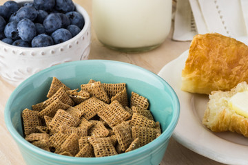 Bowl with wheat cereal and fresh croissantsl for breakfast.