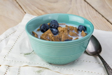 Bowl with wheat cereal, blueberries and milk for breakfast.