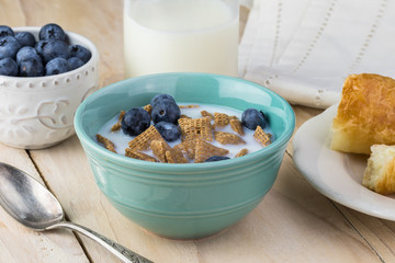 Bowl with wheat cereal, blueberries and milk for breakfast.
