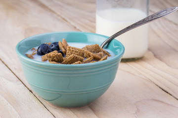 Bowl with wheat cereal, blueberries and milk for breakfast.