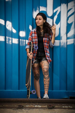 attraktive tätowierte junge Frau mit Longboard 