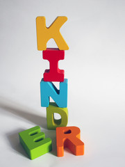 Kinder: bunte Holzbuchstaben aufgetürmt