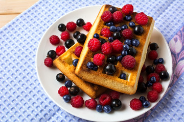 Breakfast waffles with fresh berries on the blue linen napkin