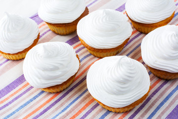 Cupcakes with white whipped cream on the striped linen napkin to
