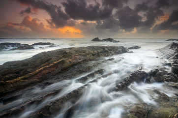 Fototapeta premium Unique rock formation hitted by wave with dramatic Rays of Light