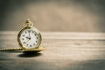 Old vintage gold pocket watch on wooden floor.