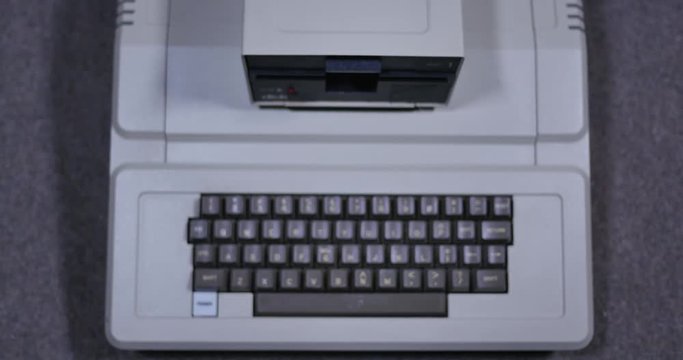 Overhead shot of someone inserting and removing an old-style 5.25-inch floppy disk. Shallow depth of field.	 	