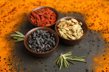 Dried spices in bowls on color background