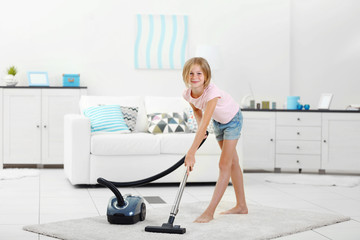 Little girl vacuuming floor with hoover