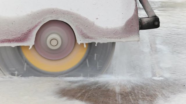 A worker cutting concrete road with diamond saw blade machine