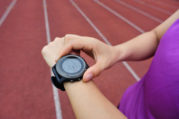 young woman runner ready to run set and looking at sports smart watch