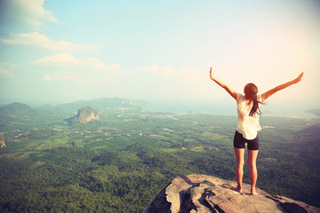 young freedom woman open arms on mountain peak