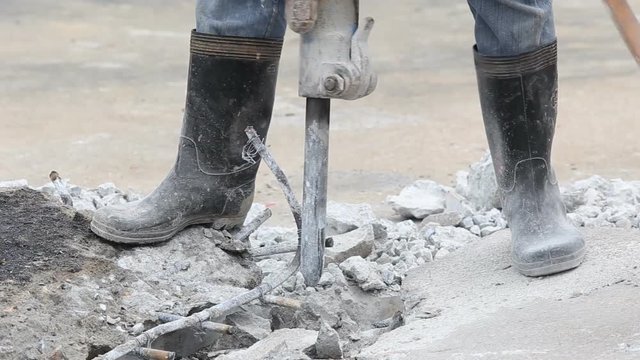 Construction worker removes excess concrete with drilling machine