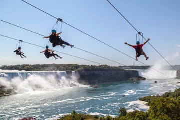  Four unrecognizable people  taking zipline ride at Niagara Falls, Ontario.  New zipline in Niagara Parks opened in the summer of 2016   © JHVEPhoto