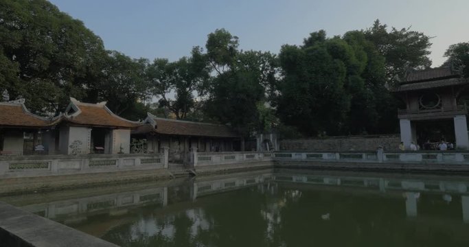 Panning shot of tourists visiting the Temple of Literature. Third Courtyard with pool in foreground. Hanoi, Vietnam
