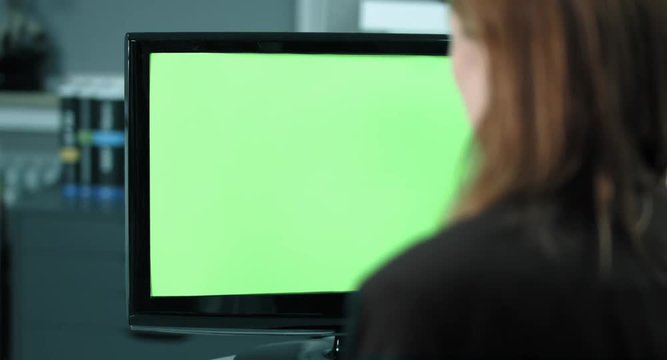 4K: Eine weibliche Angestellte arbeitet am Bildschirm. Der Fokus verl&auml;uft vom Bildschirm zu ihrem Gesicht. Der Bildschirm ist chromagr&uuml;n.