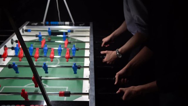 Happy group of friends playing kicker in the bar. Table football. Closeup. 4K.
