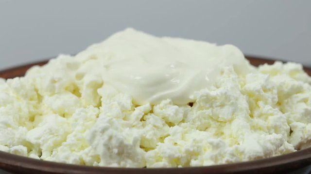 Cottage cheese, sour cream and honey in plate. Rotates plate with cottage cheese . Close up