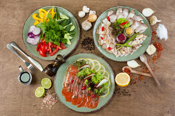 Different vegetables, meat, red fish and other dishes, sauces, snacks and spices on a wooden background