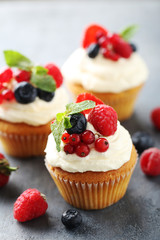 Tasty cupcakes with berries on grey table
