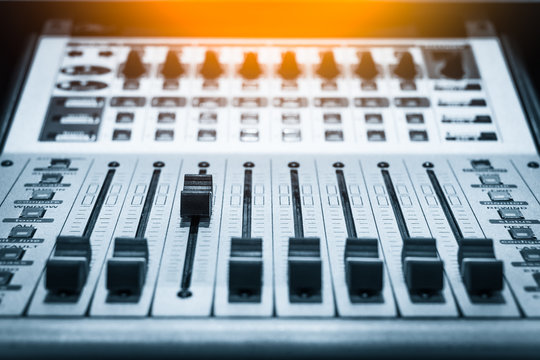 digital music studio mixer, shallow dept of field & focus on third track fader for recording or TV / radio broadcast background concept = you can be the leader in your business