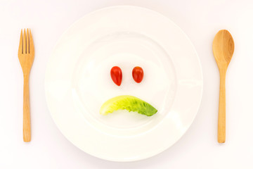 Sad face made of vegetables on the plate. Unhappy eating healthy vegetables