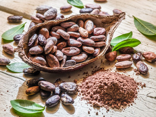 Cocoa powder and cocoa beans on the wooden table.
