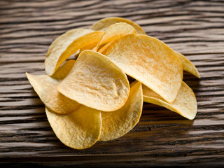 Potato chips on a wooden background.