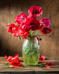 Naklejka premium Bouquet of poppy flowers in the vase on the wooden table.