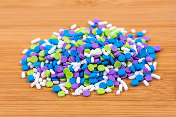 Multicolored candy sprinkles isolated on wood background