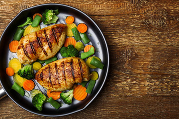 Grilled chicken breast with vegetables in a pan.