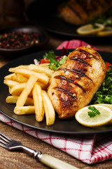 grilled chicken breast with green salad and french fries.