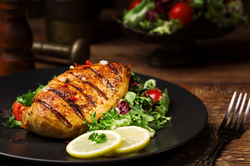 grilled chicken breast with green salad and french fries.