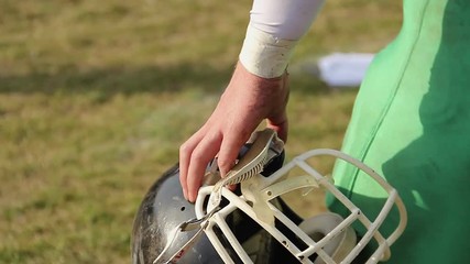 Player holding helmet, watching American football game, waiting for interchange